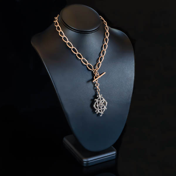 black leather neck form displaying a rose gold link necklace with diamond set monogram pendant