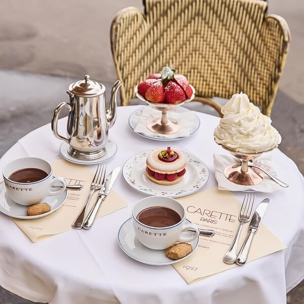 A table at set with pastries and hot chocolate outside a Paris patisserie