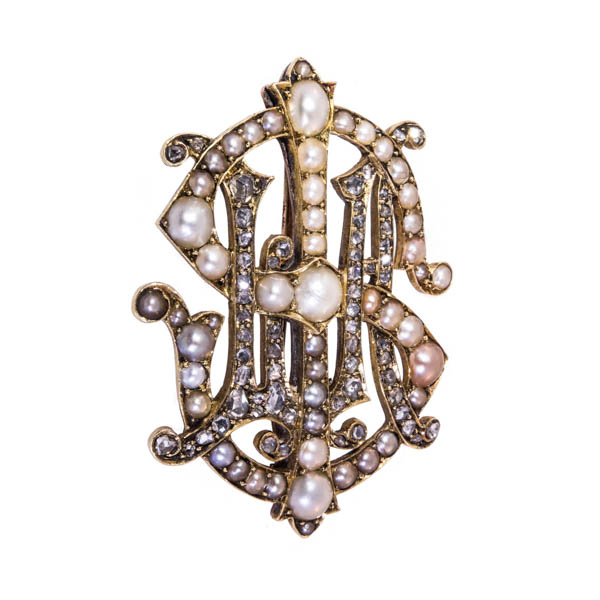 a pearl and diamond set monogram brooch against a white background