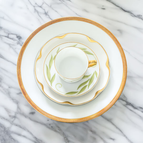 A stack of white porcelain, limoges plates all rimmed in gold